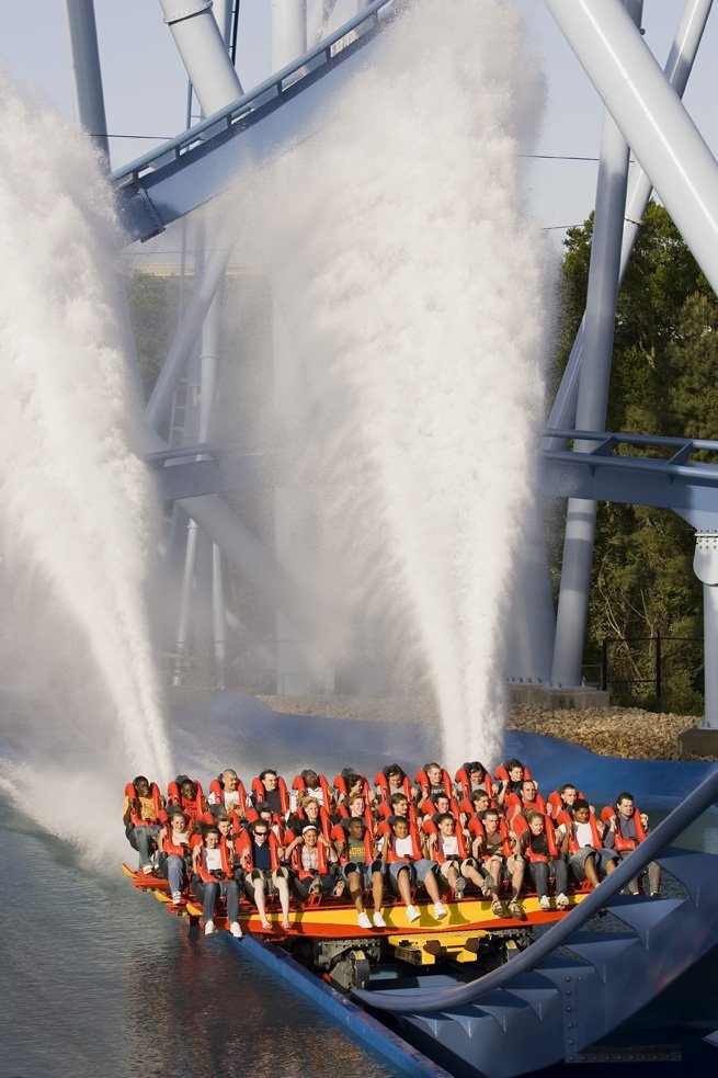 A group of people on a free hanging roller coaster that glides over water