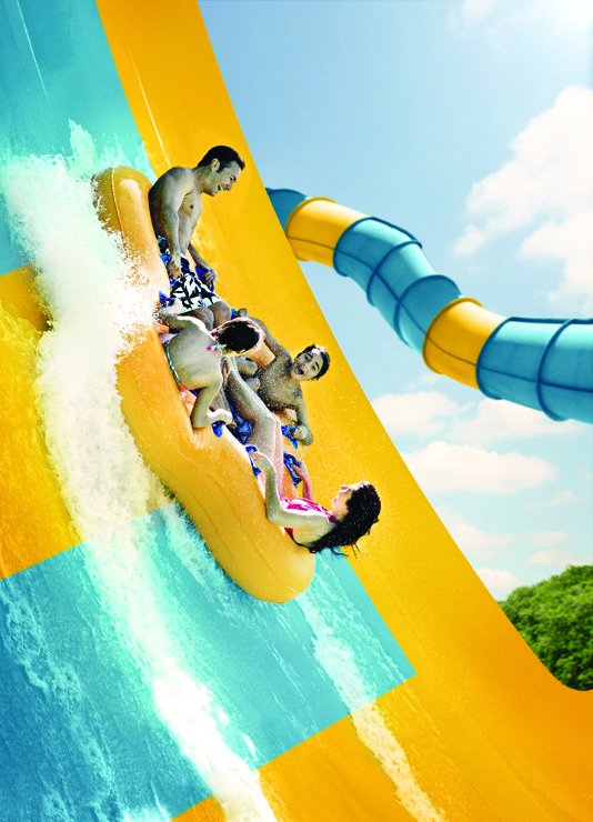 A family of four on a yellow raft going down a water slide