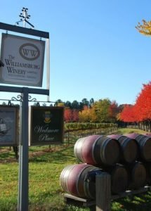 Outdoor scene with trees changing colors in the background and double stacked wine barrels on display