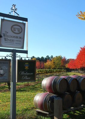 Outdoor scene with trees changing colors in the background and double stacked wine barrels on display