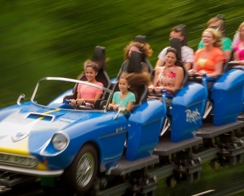 Blue and yellow roller coaster that looks like a car with people enjoying the ride