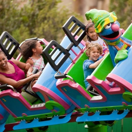 A kid's roller coaster with Grover from Sesame Street sittin gin the front