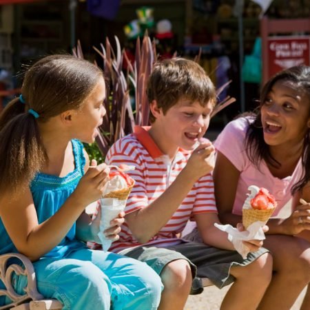 Two girls and a boy eating icecream on a bench