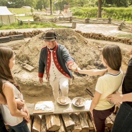 A family interacts with a Colonial Reenactor
