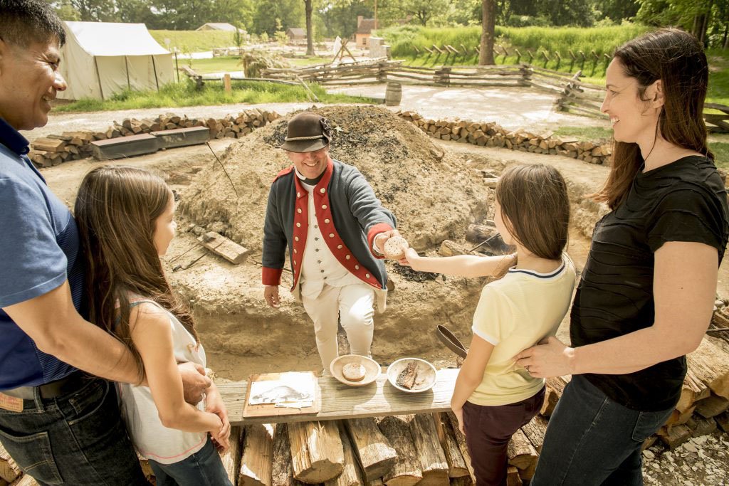 A family interacts with a Colonial Reenactor