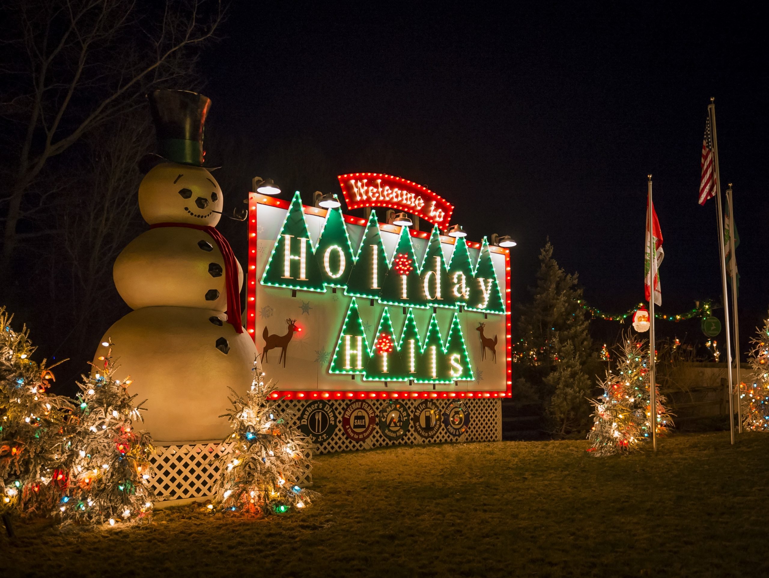 Huge Snowman in front of a lighted Christmas sign that says Welcome to Holiday Hills