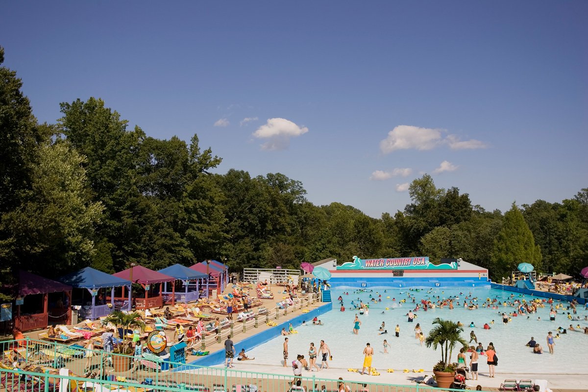 A wave pool surrounded by blue and purple cabanas and lots of people