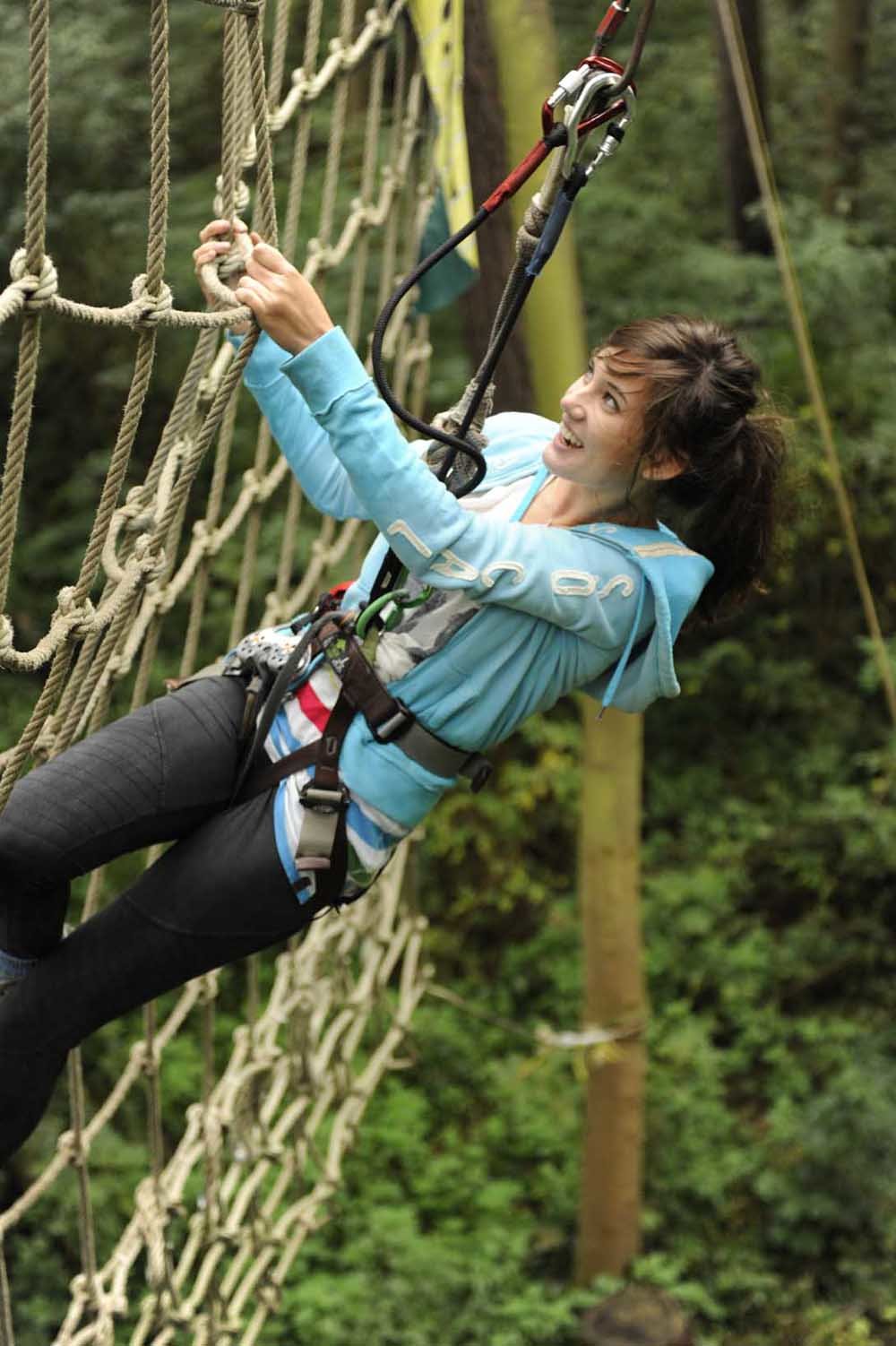 A teen girl on the cargo net in the ziplining course