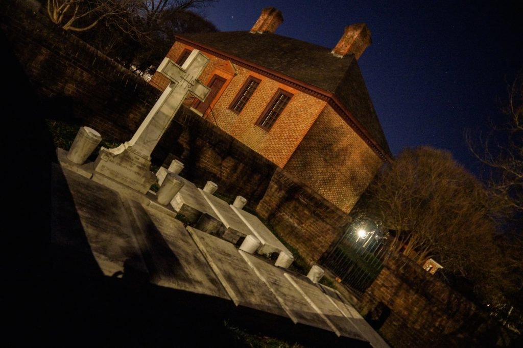 Flat grave stones with one tall cross grave stone at night