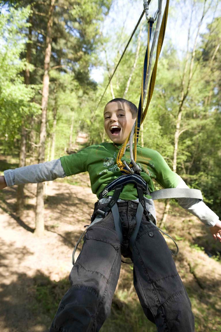 A young boy ziplining in the woods
