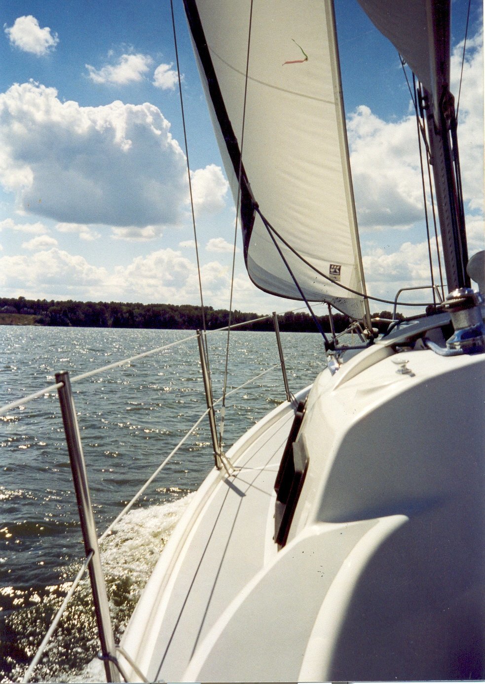 The view from the side of the sailboat with the water and shore out ahead